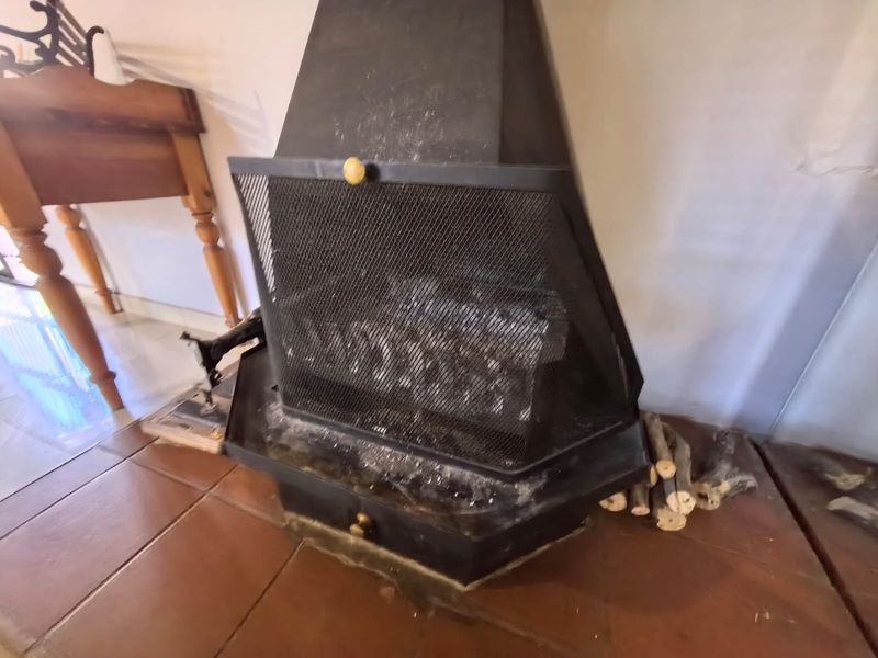 A close-up view of a black metal freestanding fireplace set on a tiled hearth within a living area.