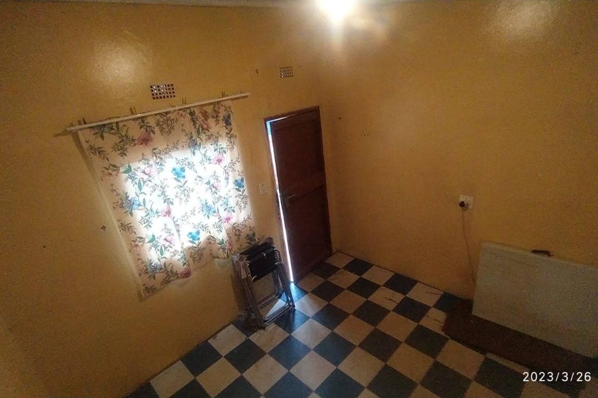 An empty living room featuring checkered floor tiles and a timber door, requiring cosmetic updates to improve its overall appeal.
