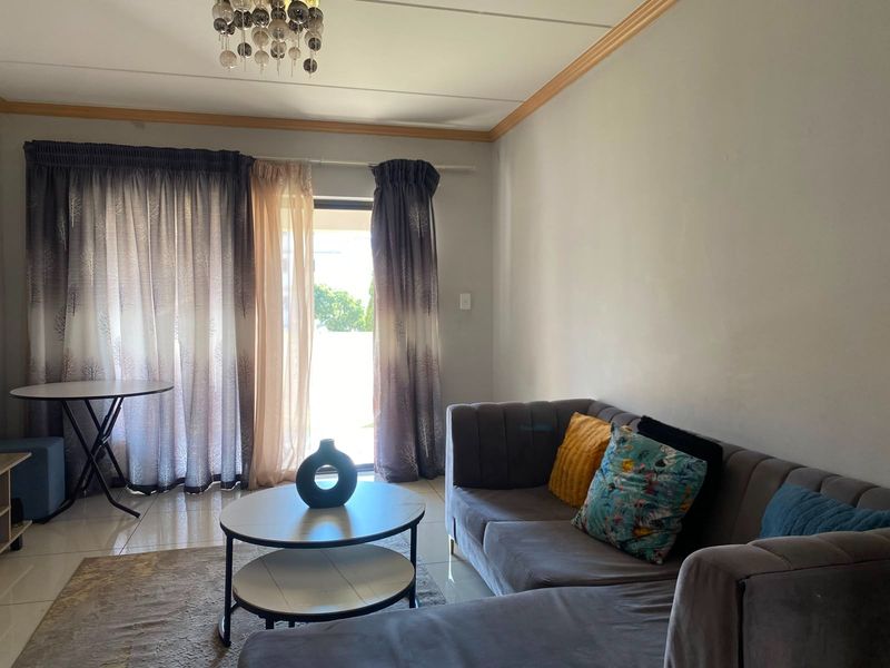 A living room featuring tiled flooring, a decorative light fixture, and a sliding glass door providing access to an outdoor area.