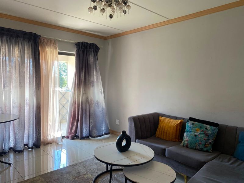 A living room featuring tiled flooring, crown molding, and a sliding glass door providing access to an outdoor balcony area.