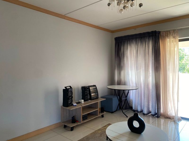 A living room area featuring tiled flooring, decorative ceiling molding, and a sliding glass door providing natural light.