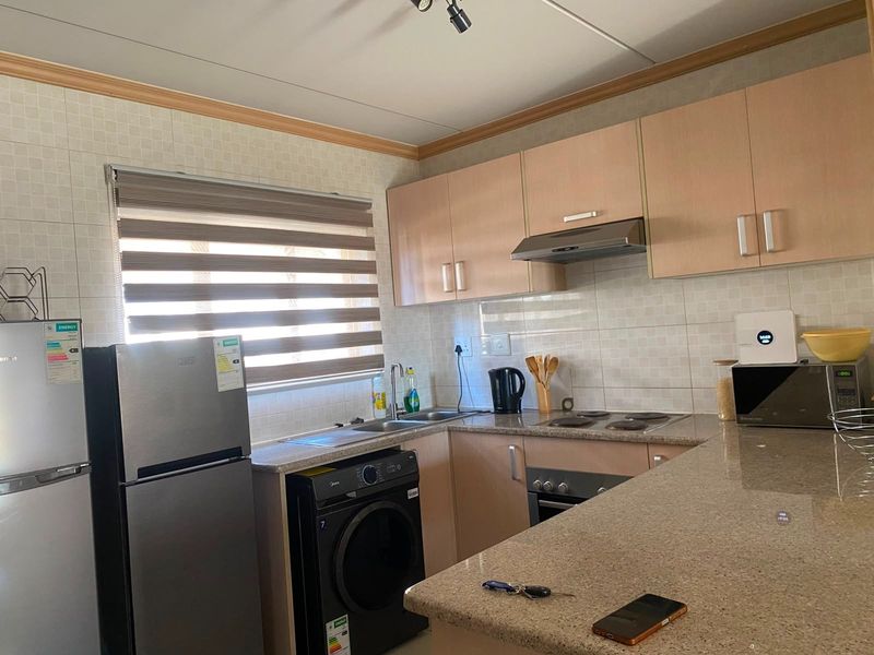 A functional kitchen featuring laminate cabinetry, granite countertops, a built-in oven with hob, and a tiled backsplash.