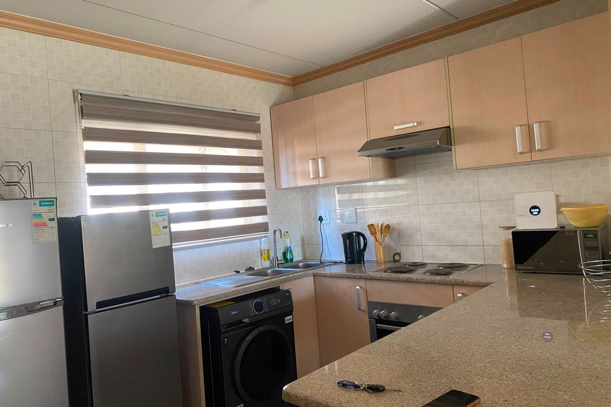 A functional kitchen featuring laminate cabinetry, granite countertops, a built-in oven with hob, and a tiled backsplash.