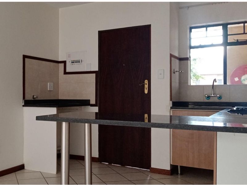 A functional kitchen featuring granite countertops, built-in cabinetry, a breakfast bar, and tiled backsplash, offering a clean and practical workspace.