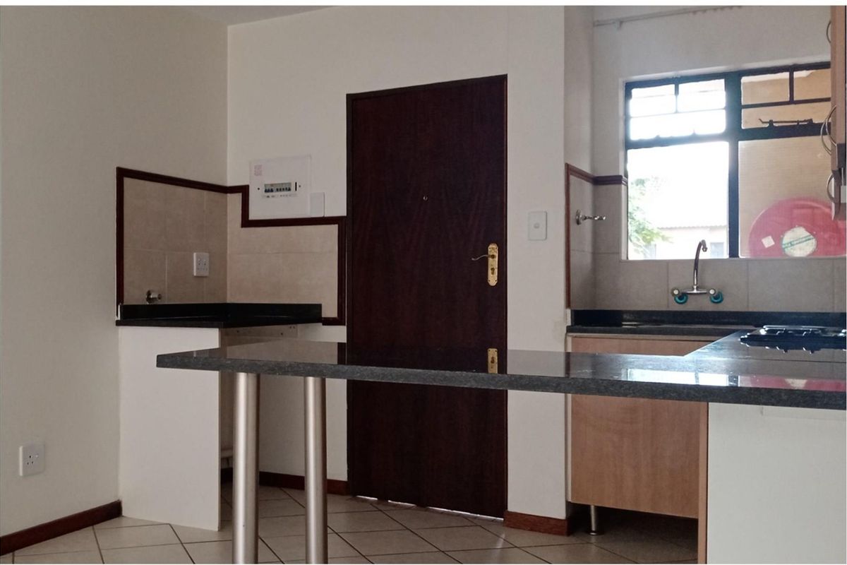 A functional kitchen featuring granite countertops, built-in cabinetry, a breakfast bar, and tiled backsplash, offering a clean and practical workspace.
