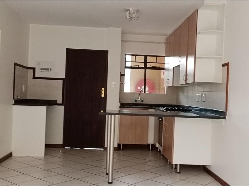 A functional kitchen featuring built-in cabinetry, laminate countertops, a hob, and an oven, with tiled flooring throughout.