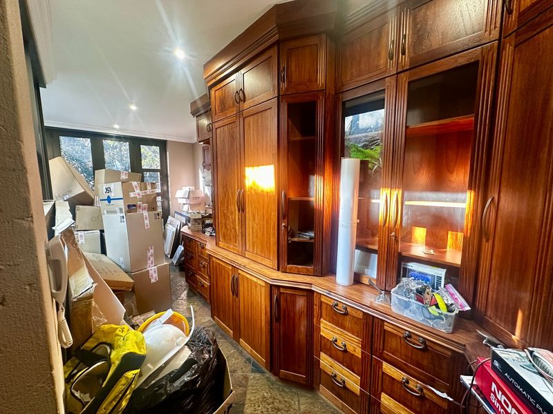 Living area featuring extensive built-in wooden cabinetry, tiled flooring, and natural light through glass-paneled doors.
