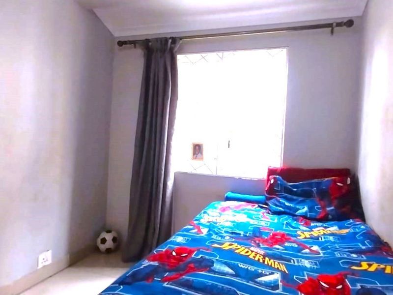A standard bedroom featuring neutral wall finishes, a window with security bars, and a curtain rod.