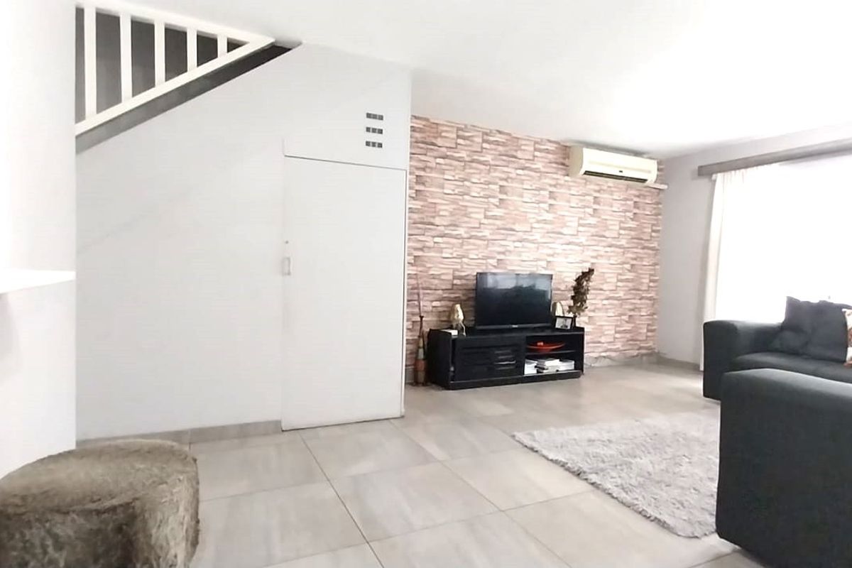 A living room featuring tiled flooring, a staircase, and a decorative feature wall with an integrated air conditioning unit.