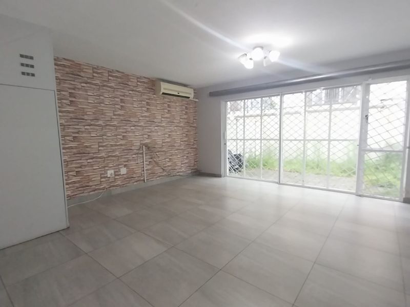 Spacious living area featuring large format floor tiles, a feature wall, built-in storage, and sliding glass doors providing access to the exterior.