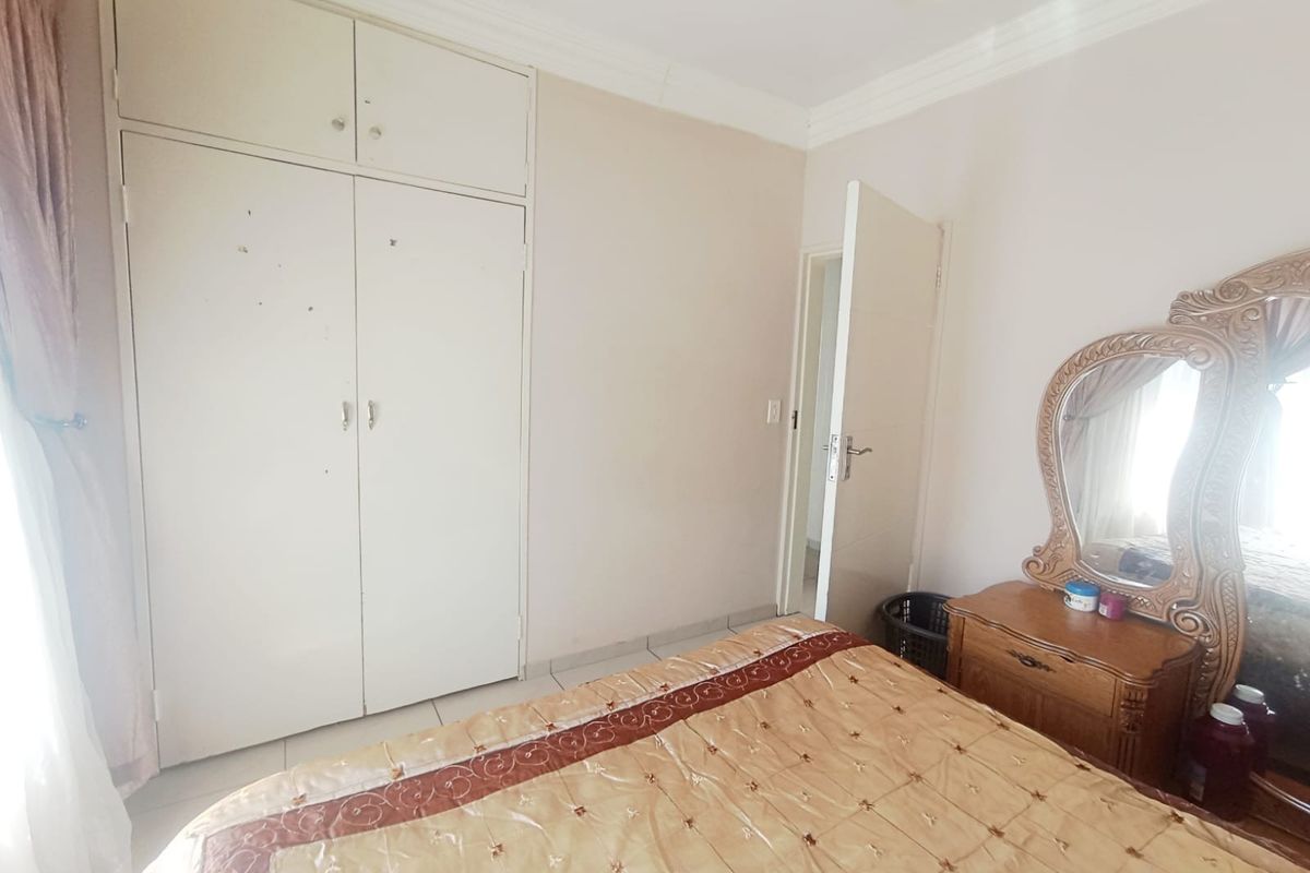A bedroom featuring tiled flooring, built-in wardrobe storage, and decorative ceiling cornicing.