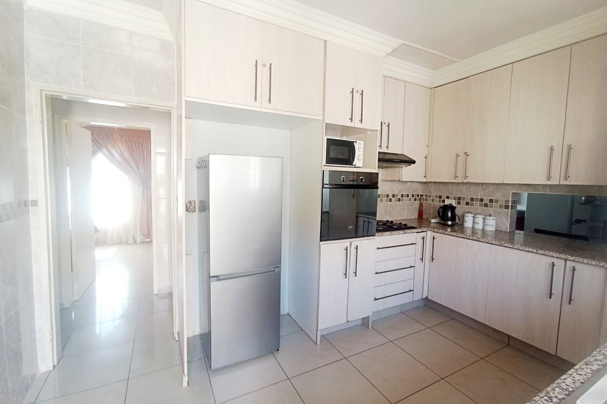 A functional kitchen featuring light-toned built-in cabinetry, granite countertops, a built-in oven, and tiled flooring, with an adjacent doorway leading to another room.