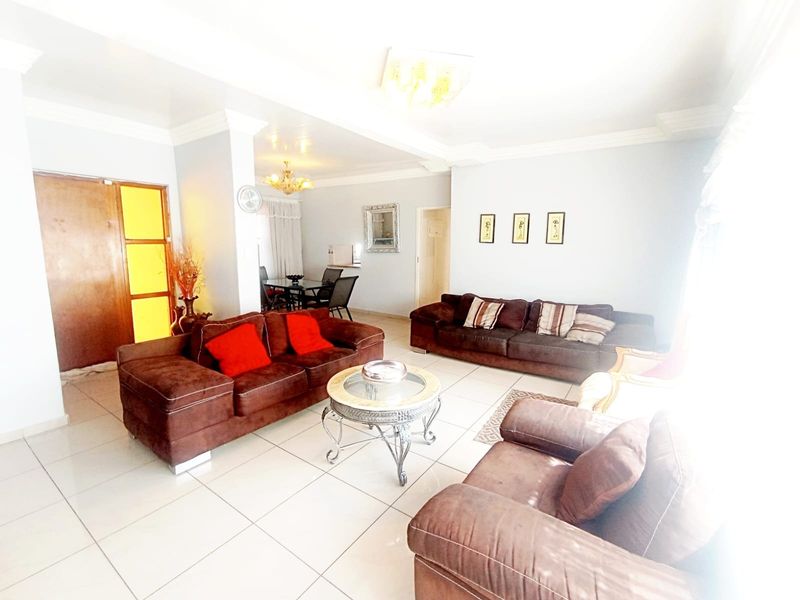 Spacious open-plan living and dining area featuring neutral tiled flooring, crown molding, and bright, airy interiors.