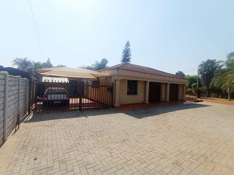 Front exterior view of the property featuring a paved driveway, secure gated entrance with a shade sail carport, and a tiled roof structure.