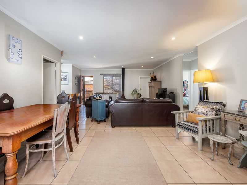 Spacious open-plan living and dining area featuring neutral wall tones, tiled flooring, recessed lighting, and a cozy freestanding fireplace.