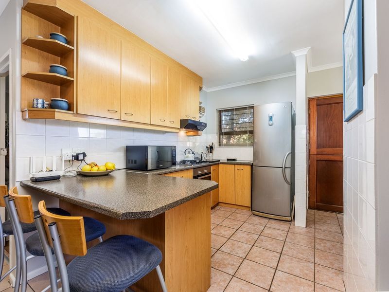 A functional kitchen featuring light wood cabinetry, laminate countertops, a breakfast bar, and tiled flooring, providing a practical layout for daily meal preparation.
