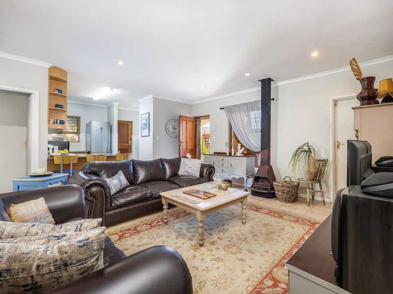 Open-plan living area featuring a freestanding fireplace, tiled flooring, recessed lighting, and an integrated kitchen space with built-in cabinetry.
