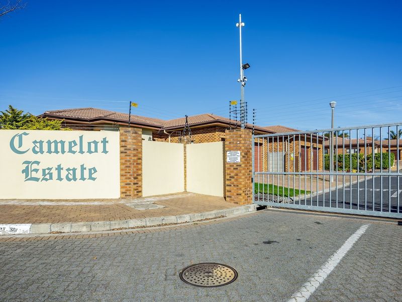 The entrance to Camelot Estate featuring a secure gated access point, brick boundary walls, and electric fencing for enhanced security.
