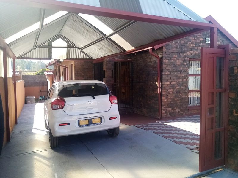 Front exterior view of the property featuring a face brick facade, a covered carport, and a paved driveway entrance.