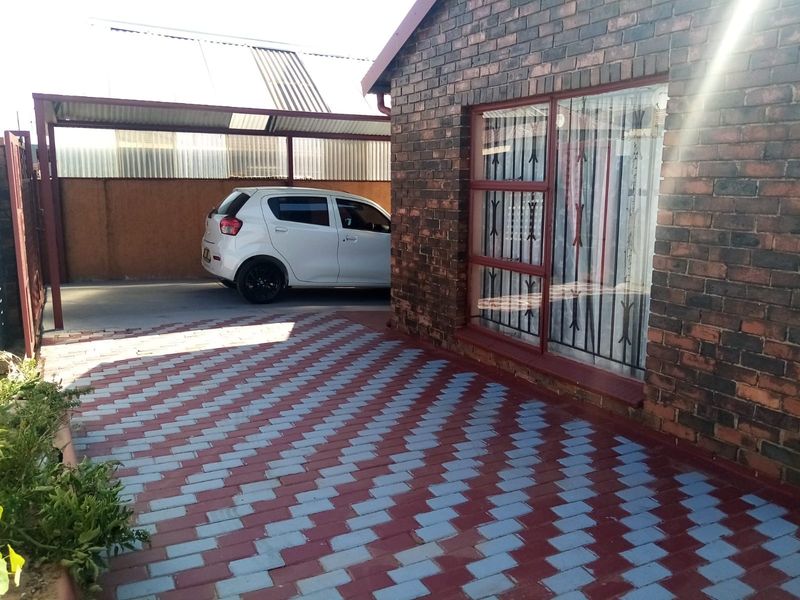 Front exterior view of a face brick house featuring a paved driveway and a covered carport area.