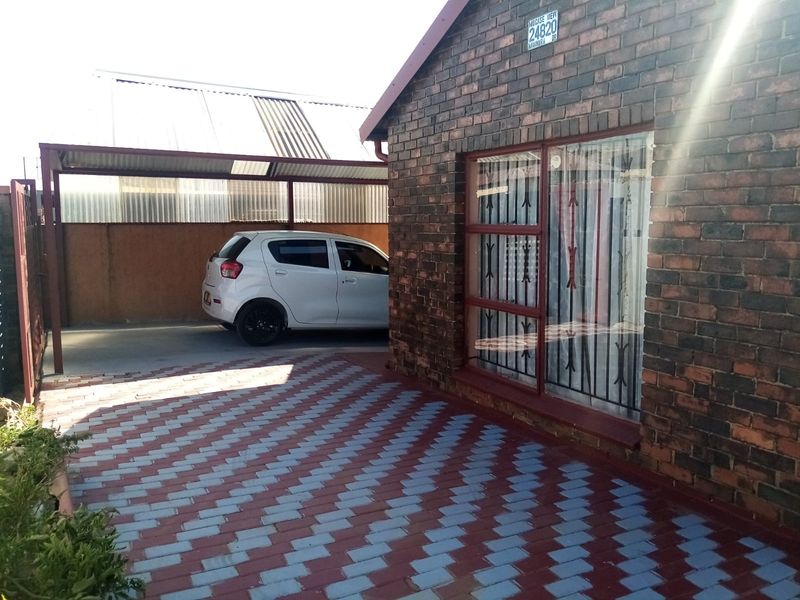 Front exterior view of a face brick house featuring a paved driveway and a covered carport area.