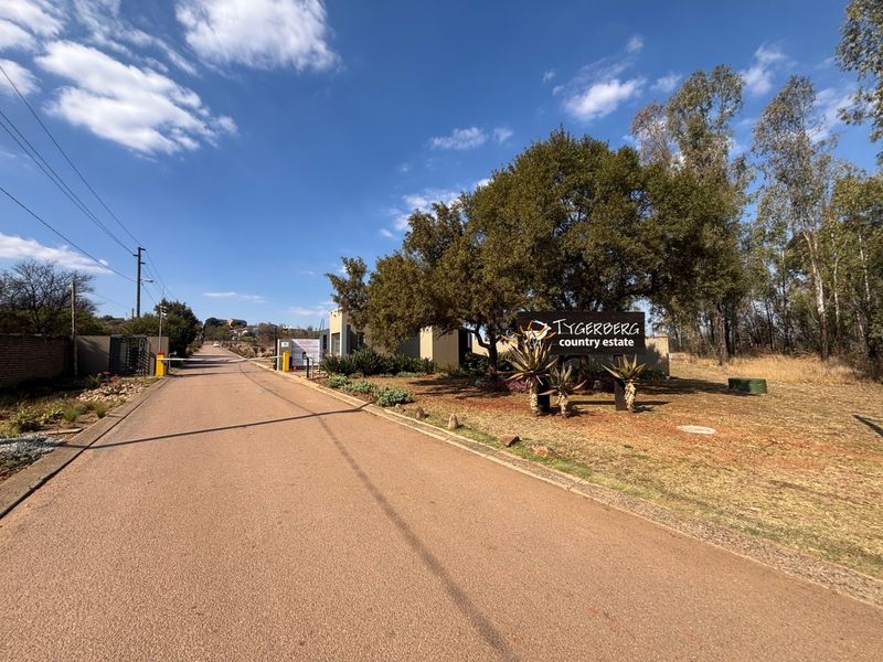 Entrance view of Tygerberg Country Estate featuring a paved access road, security gate, and established estate signage.