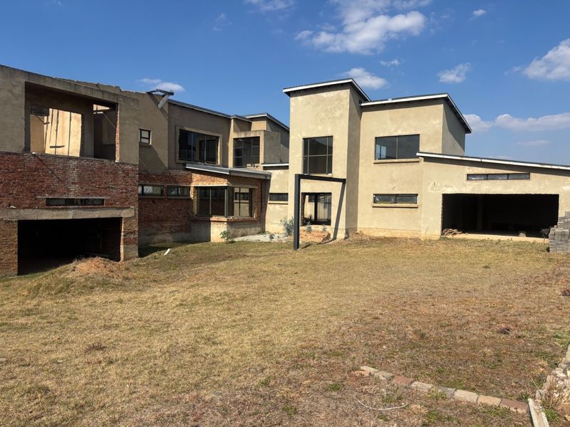 Rear view of a large residential property currently under construction, featuring exposed brickwork and unfinished exterior surfaces.