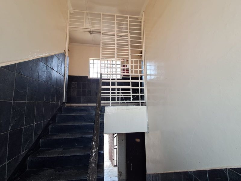 Interior staircase area featuring dark tiled wall accents, a security gate, and a window with security bars.