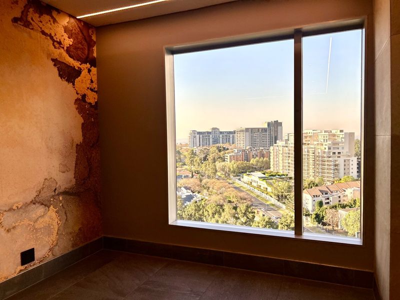An interior view of a room featuring a large picture window with an expansive urban outlook and a textured feature wall.