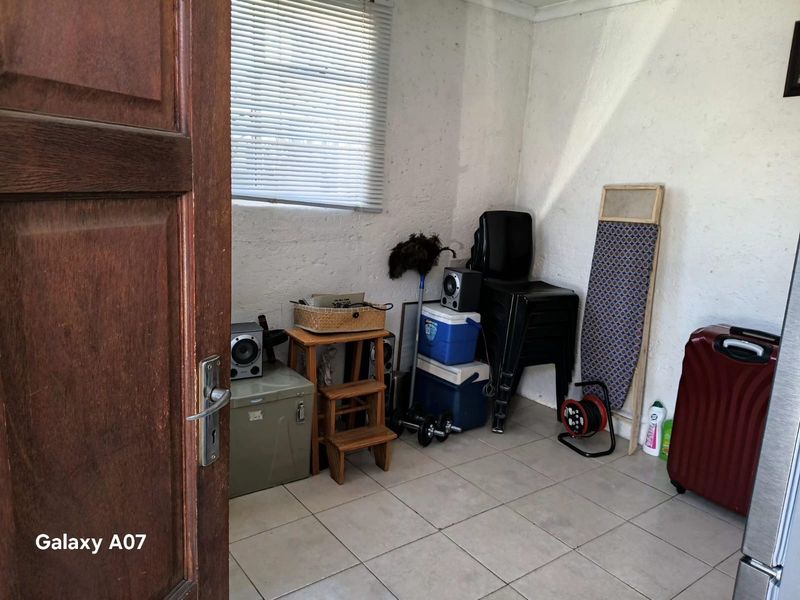 A functional utility space featuring tiled flooring and a window with venetian blinds, suitable for storage or laundry use.
