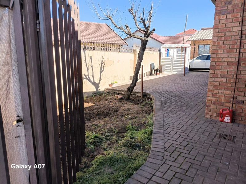 Rear courtyard area featuring brick paving, a boundary wall, and a small garden bed.