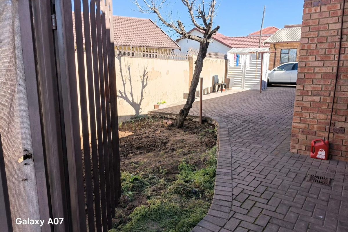 Rear courtyard area featuring brick paving, a boundary wall, and a small garden bed.
