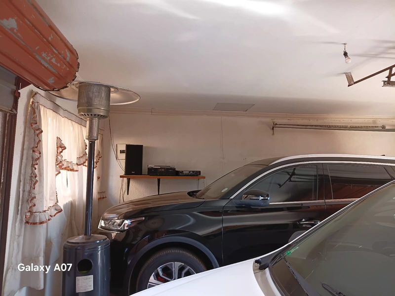 A functional garage space with overhead door mechanisms and basic lighting, currently used for vehicle storage.