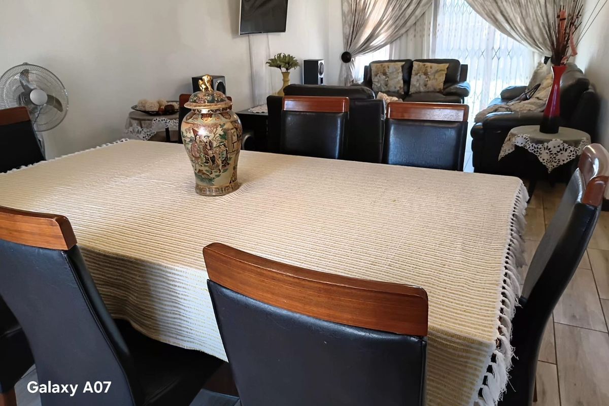 A combined living and dining area featuring tiled flooring and access to the exterior through a security gate.