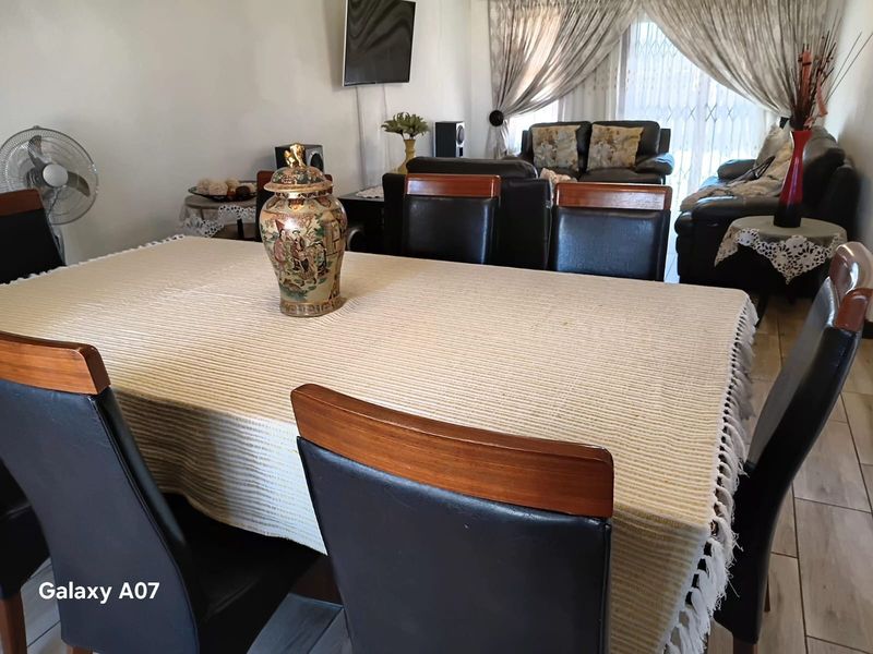 A combined living and dining area featuring tiled flooring and access to the exterior through a security gate.
