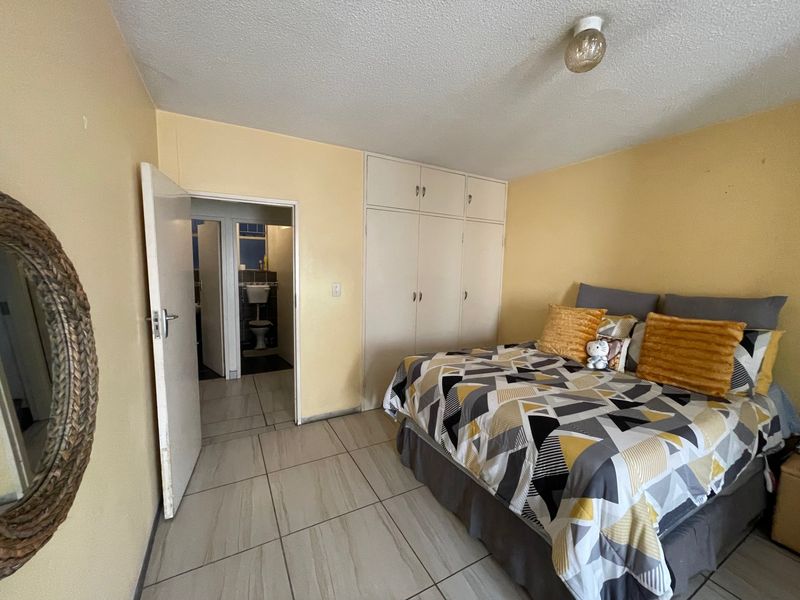 A bedroom featuring tiled flooring, built-in cupboards, and direct access to an adjacent bathroom.