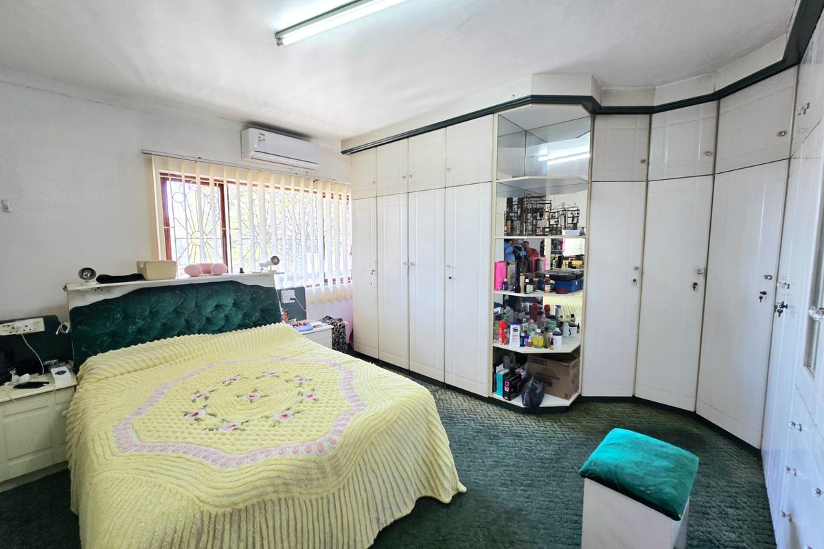 A bedroom featuring extensive built-in cabinetry, a split-system air conditioner, and security bars on the window.