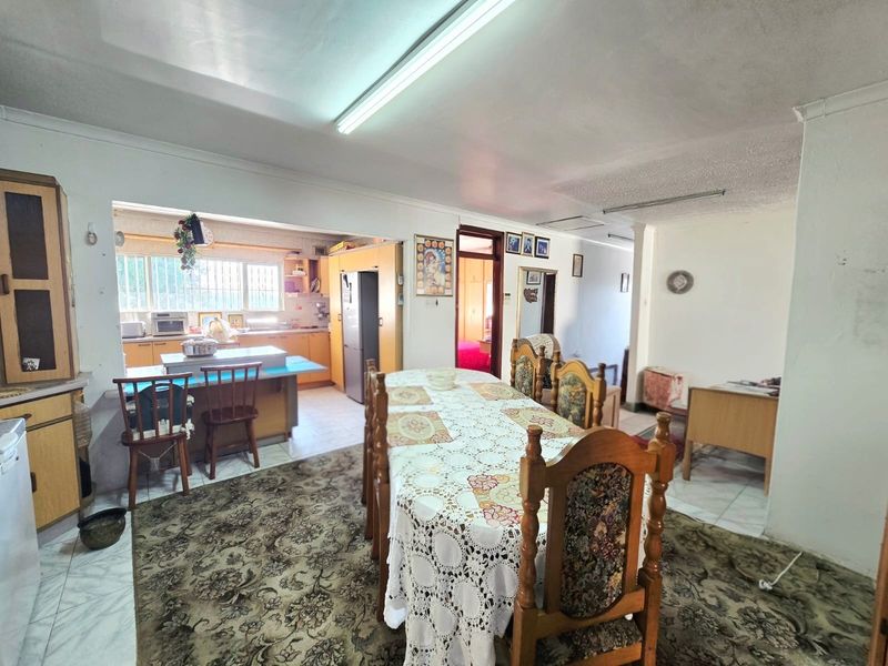 Open-plan dining and kitchen area featuring dated cabinetry, mixed flooring, and fluorescent lighting, offering potential for a modern renovation.
