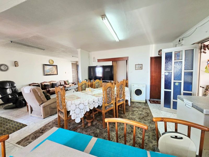 Open plan living and dining area featuring tiled flooring and a functional layout, suitable for modernization and cosmetic updates.