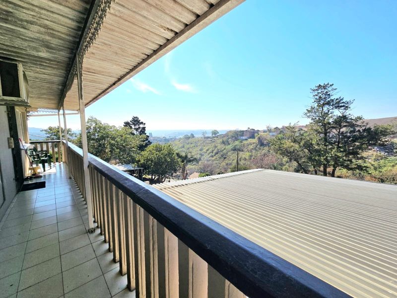 A covered balcony featuring tiled flooring and a scenic elevated view of the surrounding landscape and hills.