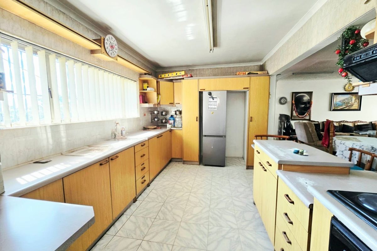 A functional kitchen featuring extensive laminate cabinetry, ample countertop workspace, built-in oven, and tiled flooring, offering a practical layout for daily use.