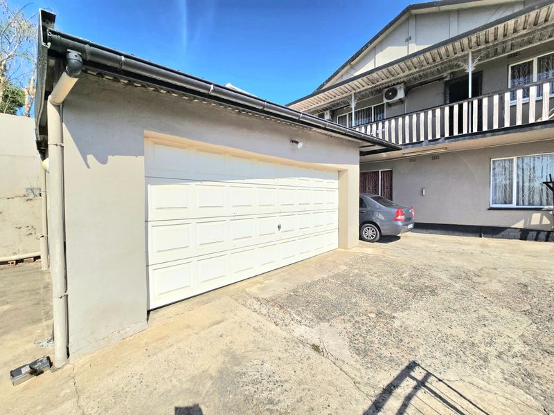 Exterior view of a residential property featuring a single garage with a sectional door and a concrete driveway, adjacent to the main building structure.