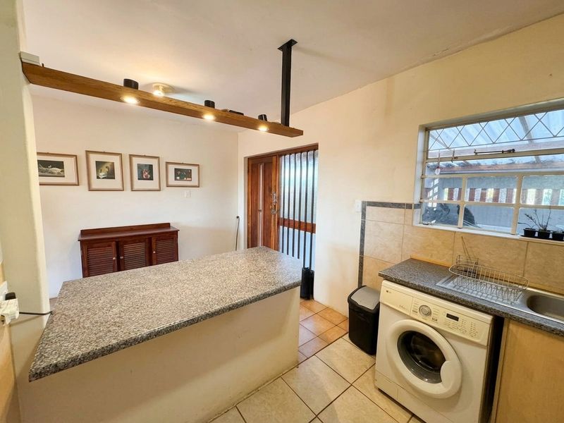 Functional kitchen featuring granite countertops, a breakfast bar, tiled flooring, and direct access to a secure exterior entrance.