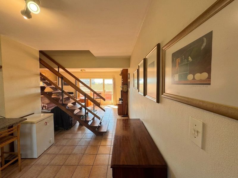 Open plan living area featuring tiled flooring, an open staircase, and sliding glass doors leading to an outdoor space.
