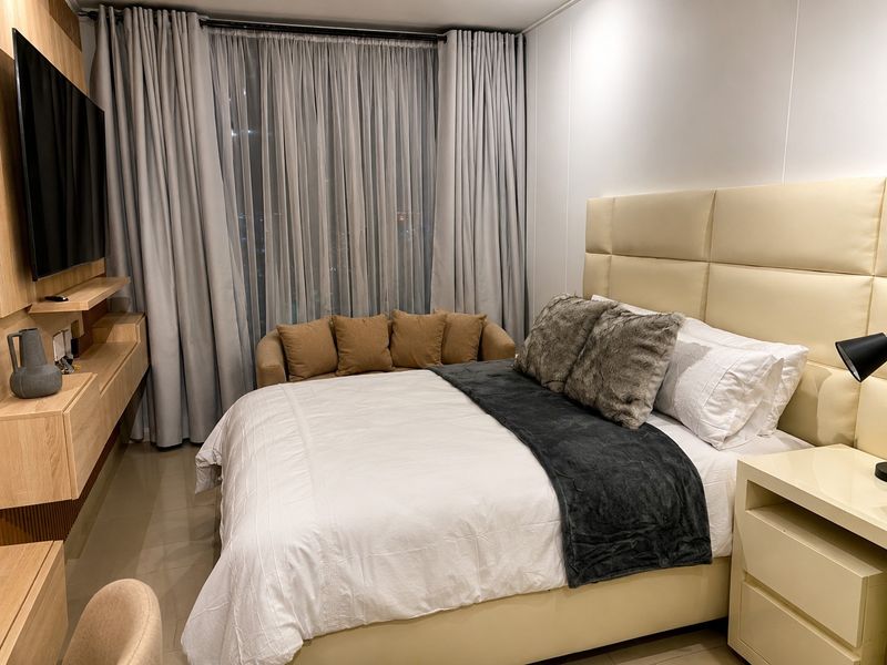 A well-maintained bedroom featuring built-in cabinetry, tiled flooring, and a large upholstered headboard, creating a comfortable and modern living space.