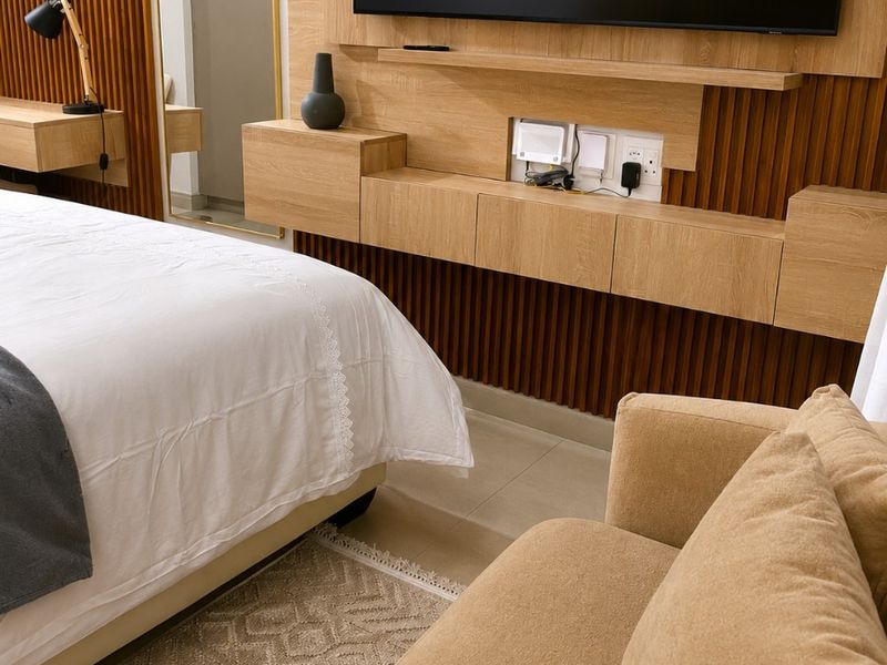 Modern bedroom featuring custom timber slat wall paneling, a floating media console, and high-quality finishes throughout.