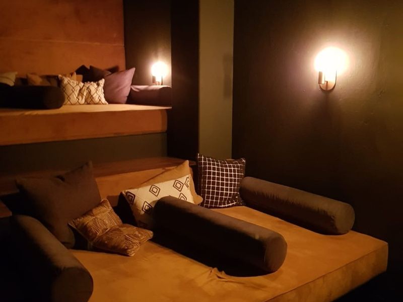 A dedicated cinema room featuring tiered built-in seating, integrated projector, and ambient wall sconce lighting for an immersive viewing experience.