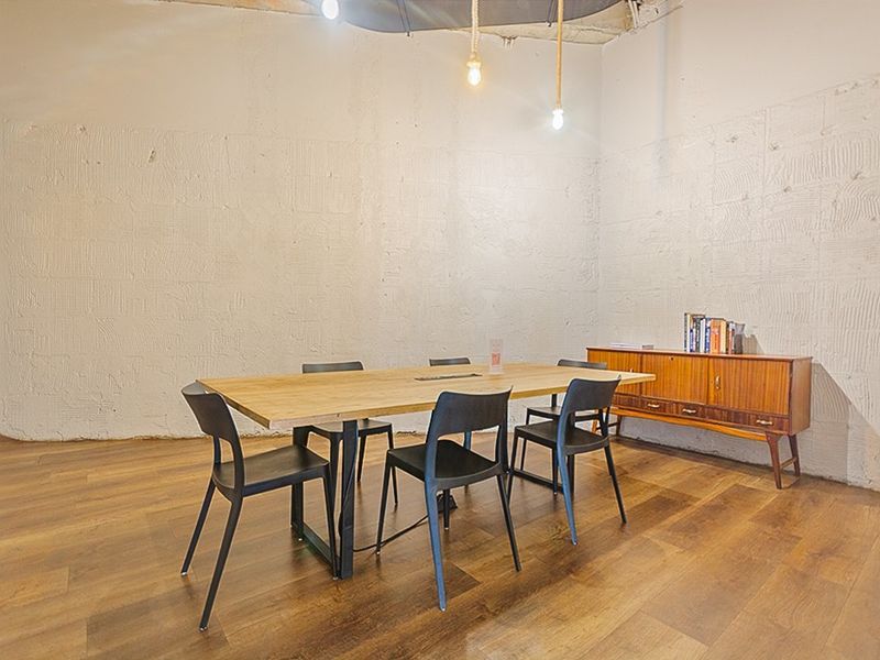 Dining area featuring laminate flooring, textured walls, and an exposed industrial-style ceiling with pendant lighting.