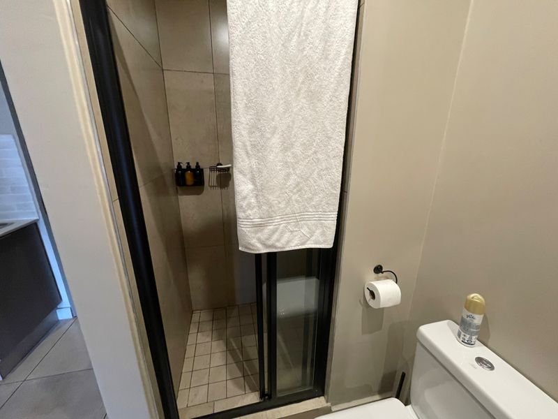 A functional bathroom featuring a tiled shower enclosure and a standard toilet, providing essential amenities in a compact layout.