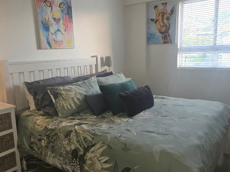 A well-lit bedroom featuring neutral walls, laminate flooring, and venetian blinds, providing a comfortable and functional living space.